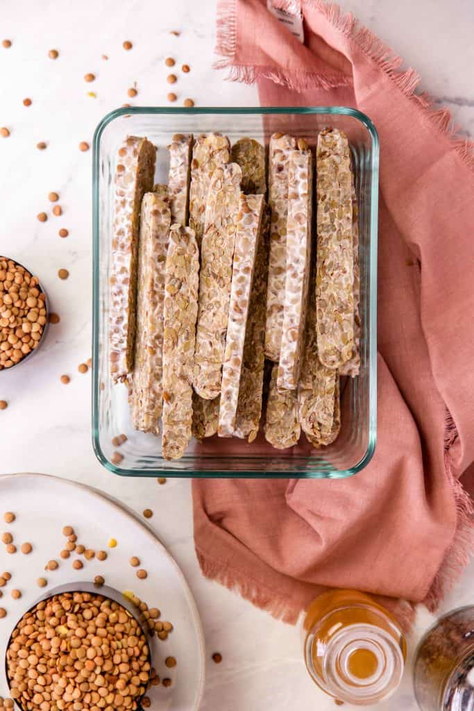 home made lentil tempeh in a glass container on a white background