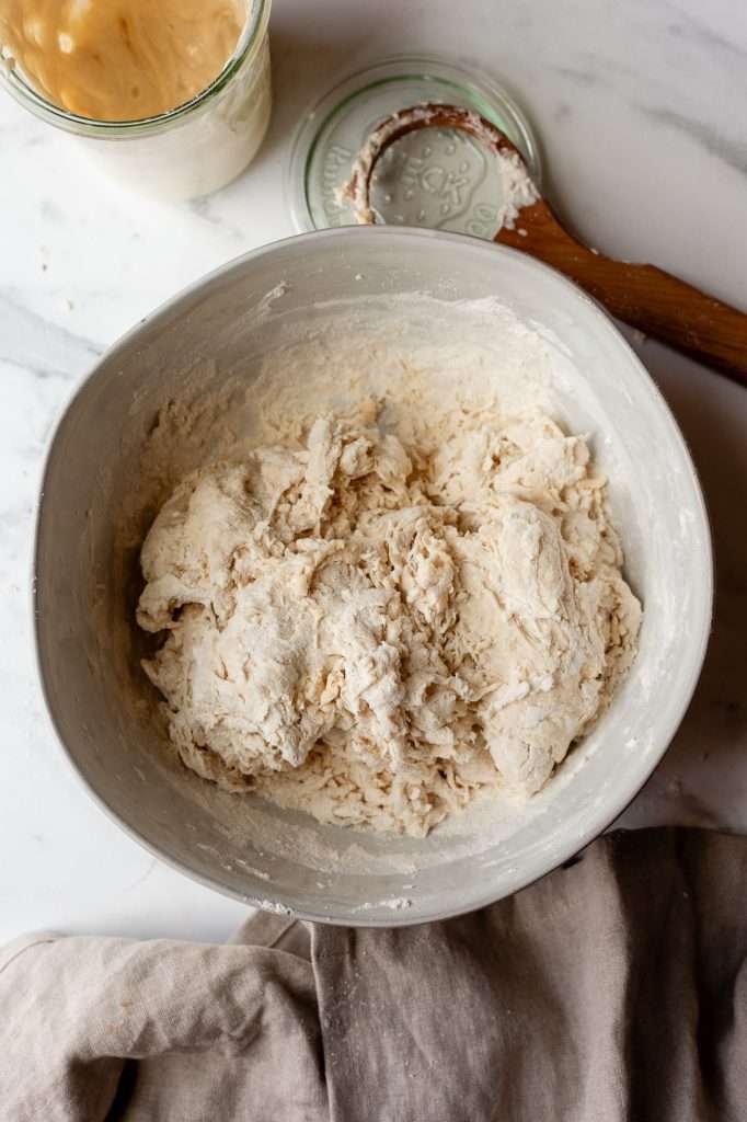 Mixing bowl with partially mixed sourdough discard bagel dough.