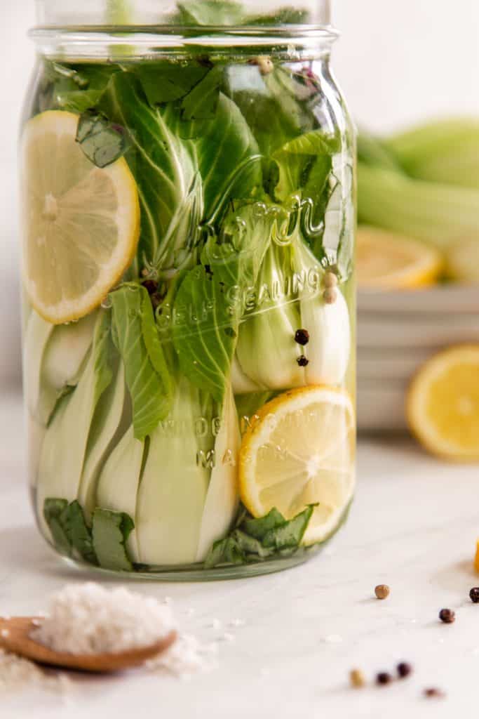 a mason jar of of baby bok choy fermenting on a counter.