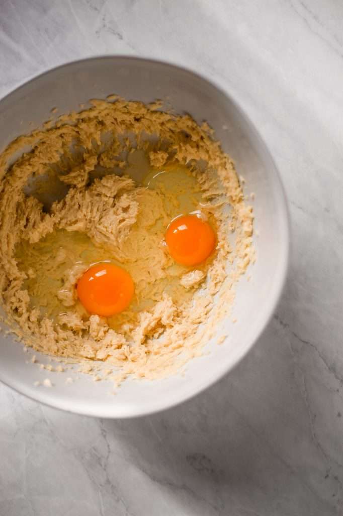 A mixing bowl with fresh egg yolks cracked on top of the sourdough dough, ready to be mixed in. 