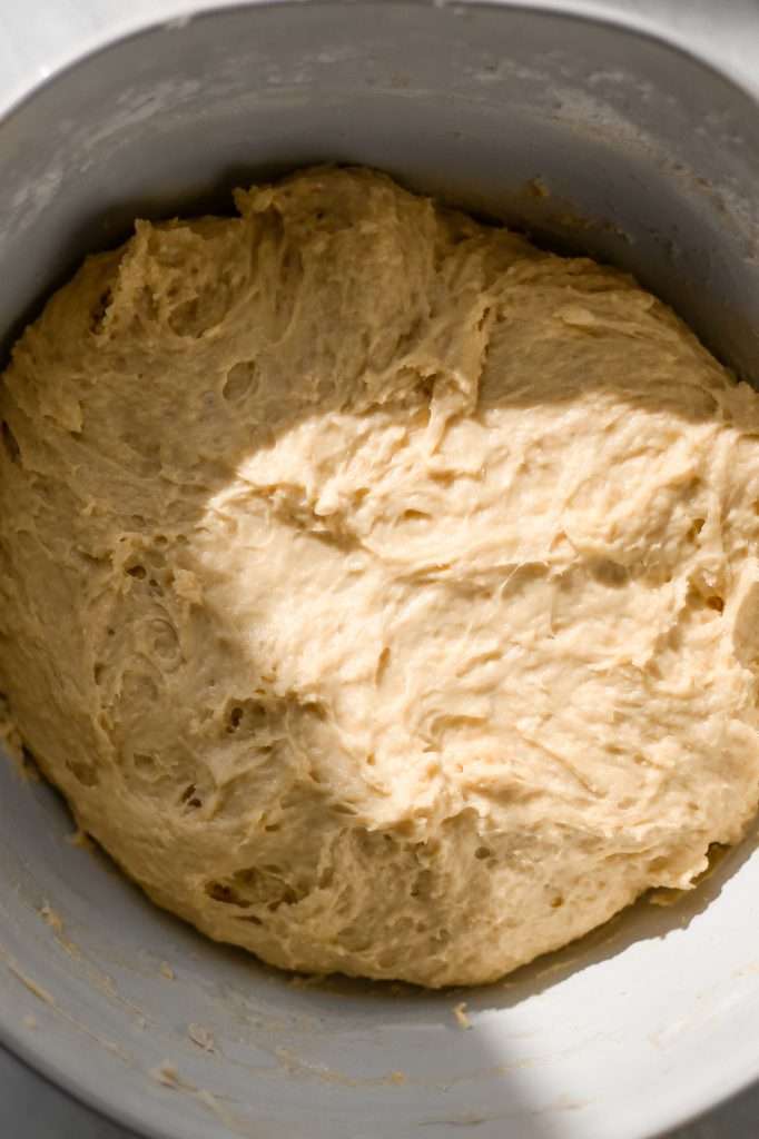 A bowl filled with freshly mixed sourdough king cake dough, showing a soft, sticky texture before bulk fermentation.