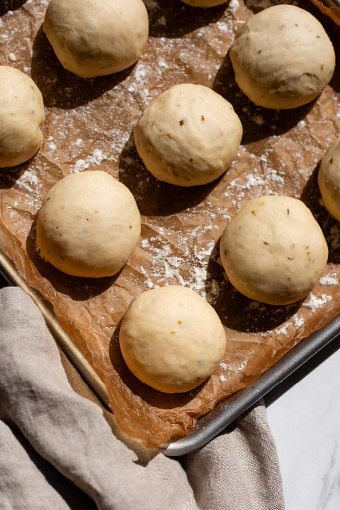 shaped sourdough dinner roll dough on a parchment paper lined pan. 