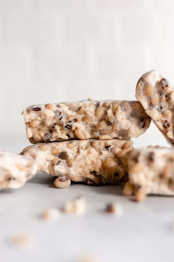 four chunks of homemade tempeh with black eyed peas, sitting on a white counter top. 