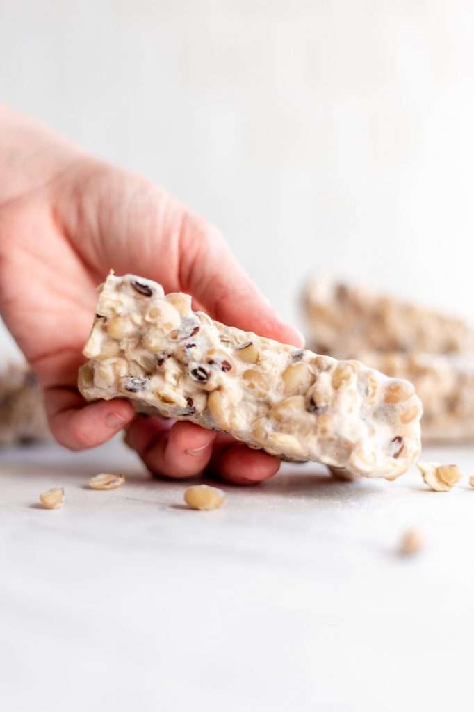 someone holding a slice of homemade tempeh with balck eyed peas in their hand. 