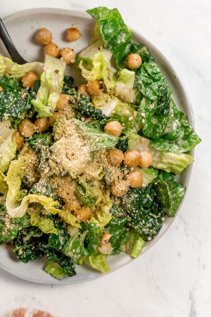 chickpea Caesar salad on a white plate topped with vegan crumbly Parmesan cheese