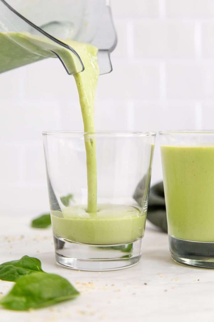 creamy minty green smoothie being poured from a blender into two cups