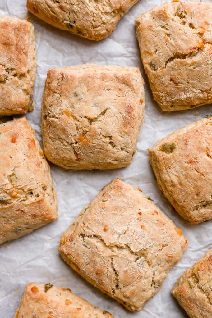 the golden brown tops of freshly baked kimchi cheddar biscuits on a white parchment paper lined pan