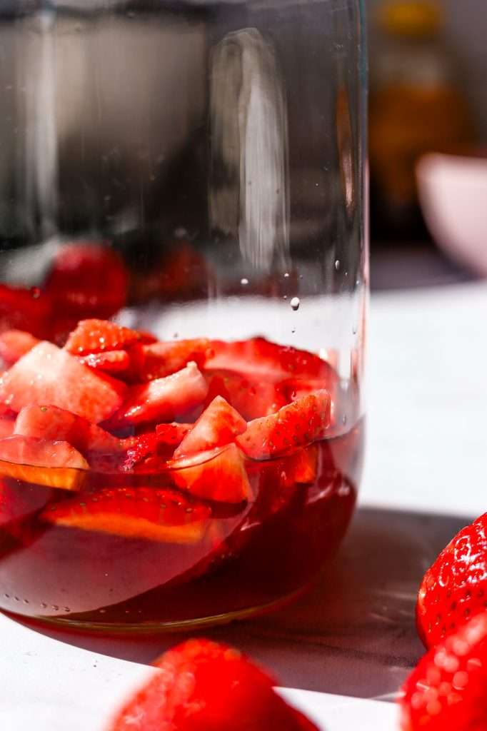 chopped strawberries in a bottle with honey for mead making. 