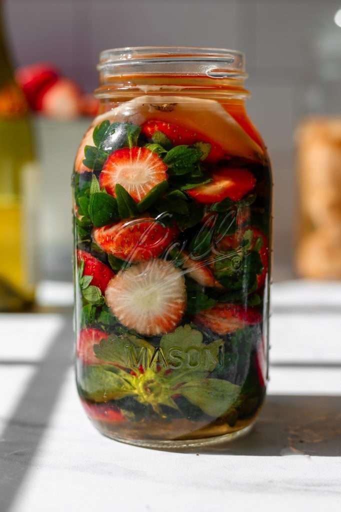 strawberry vinegar made with white wine and strawberry tops in a mason jar. 