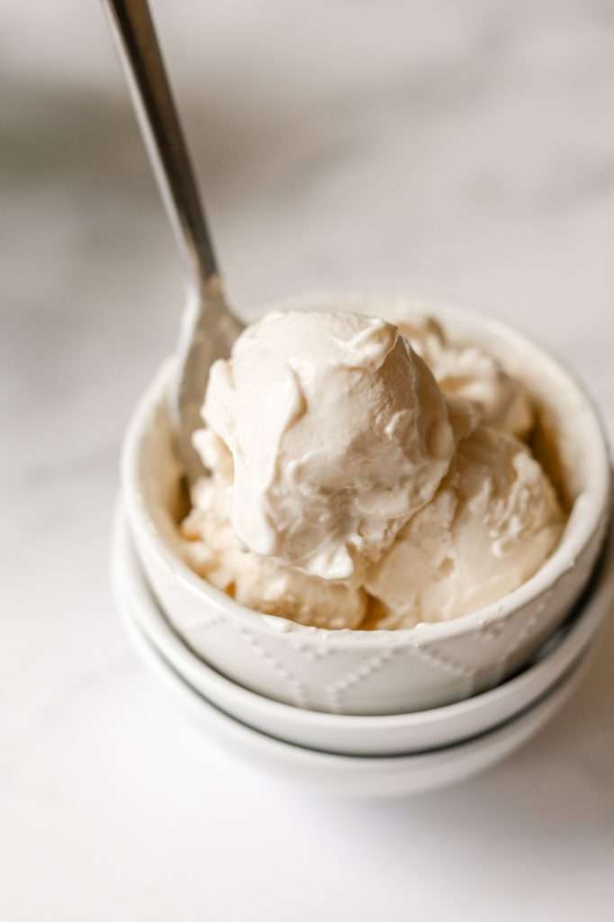 brown butter vanilla cottage cheese ice cream in a tiny white bowl with a silver spoon. 