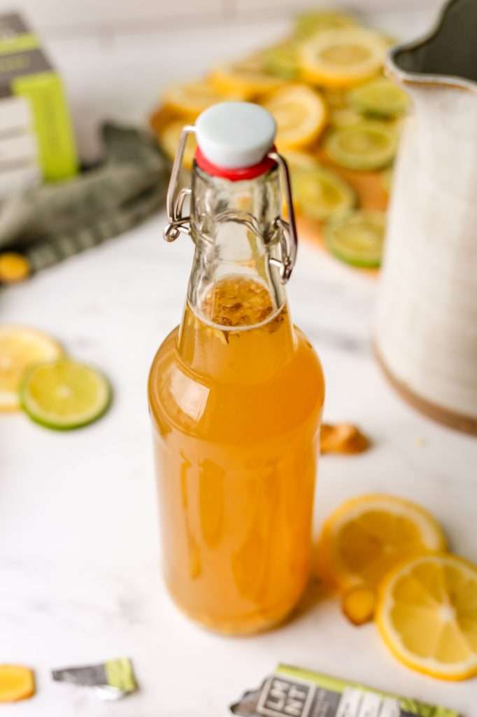 green tea kombucha in a pressure safe, sealed bottle. There are little ginger pieces floating in the bottle. 