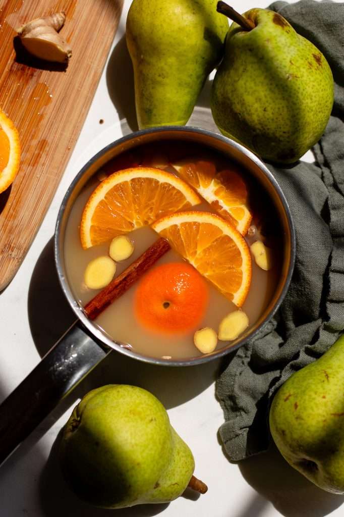 the first main step to making pear cider. Simmering some pear juice in a small pot with orange slices, a cinnamon stick, and ginger