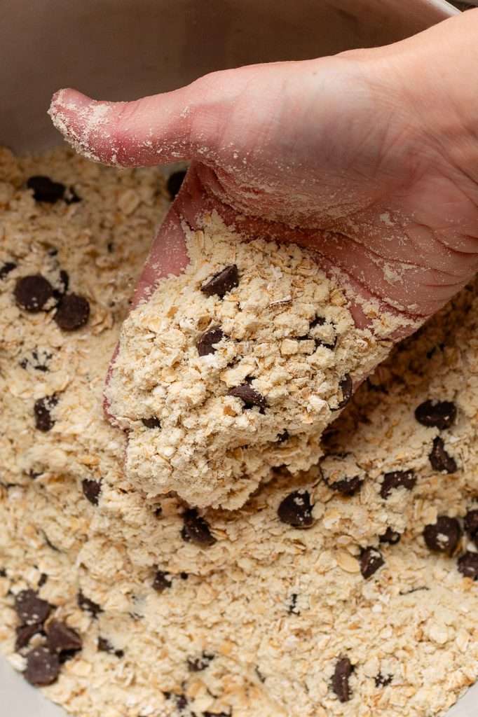 Hand mixing oats, protein powder, and chocolate chips for chocolate chip cottage cheese cookie dough.