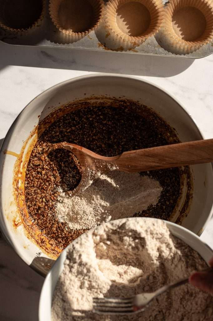 Mixing bowl with wet ingredients, including molasses, sourdough starter, and melted butter, being combined with the dry ingredients. 