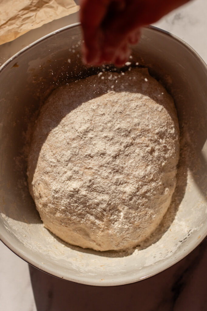 Dough for sourdough cottage cheese bagels dusted with flour in a bowl during the dough forming process.