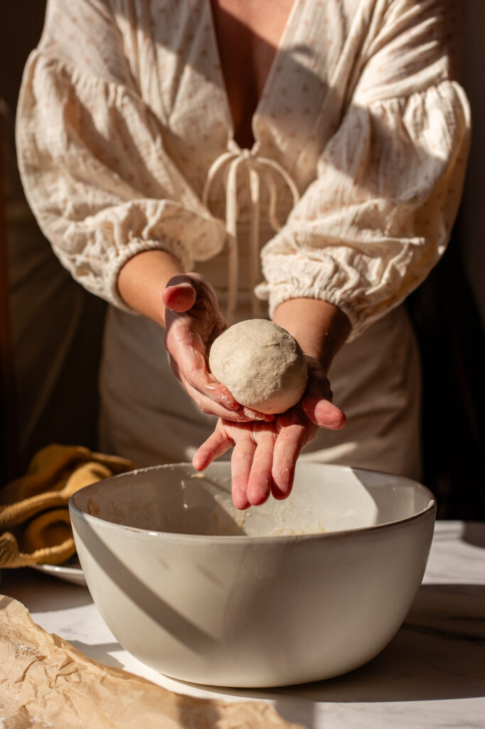 Shaped sourdough bagel dough in hand, ready to be placed for proofing.