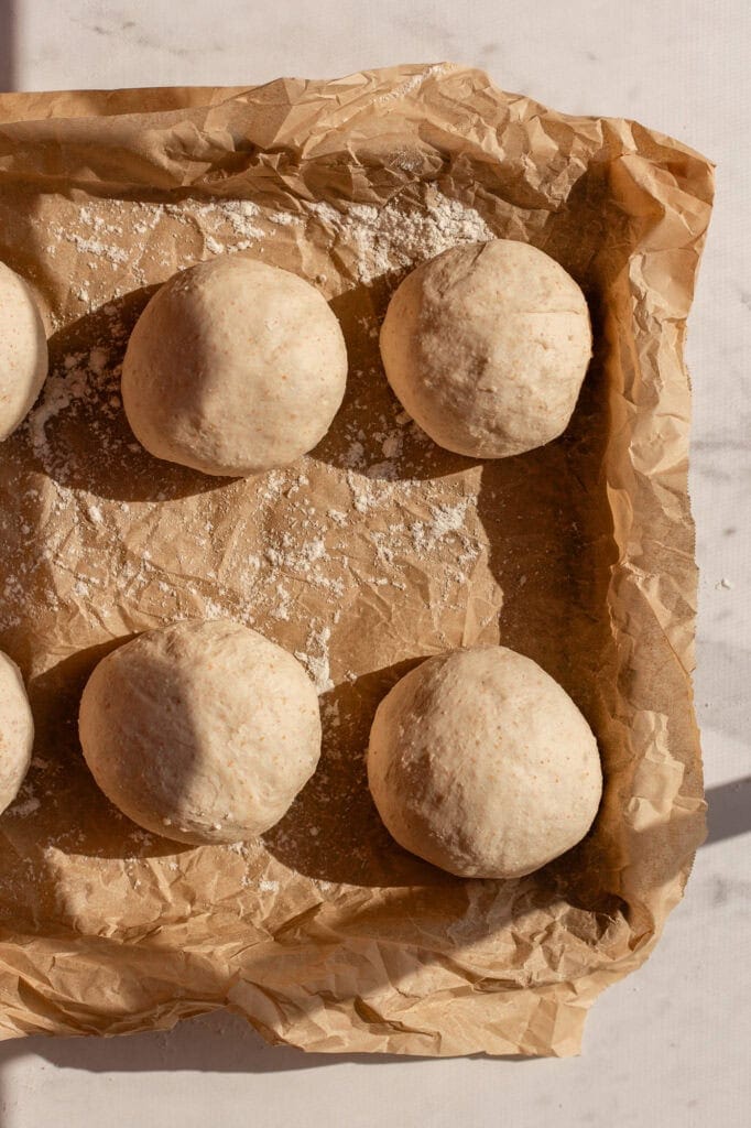 Sourdough cottage cheese bagel dough rounds resting on a parchment-lined tray for final proofing.