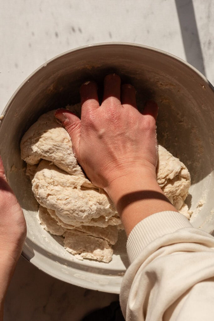 Hands folding and working the dough to incorporate the ingredients thoroughly.