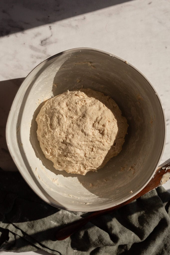 A slightly rough sourdough dough ball resting in a bowl after initial kneading.