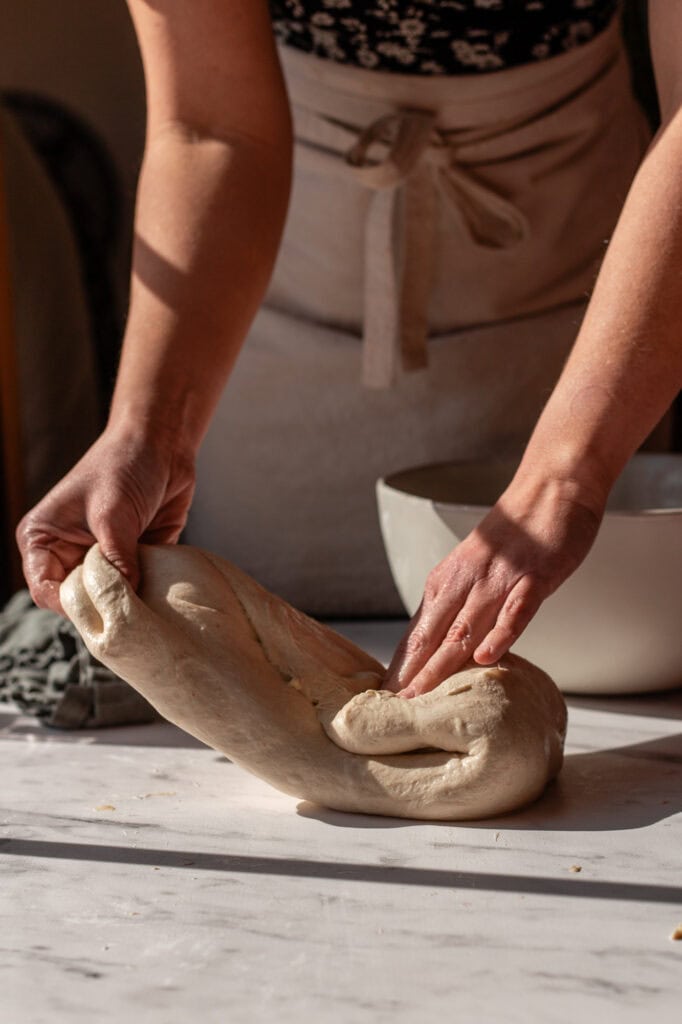 Folding sourdough dough onto itself on a slightly wet surface to maintain hydration and prevent sticking.