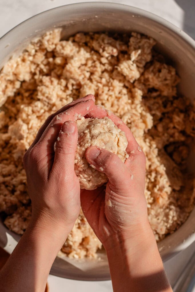 Close-up of hands smoothing and tightening a formed miso ball, ensuring it holds its shape before fermentation. 