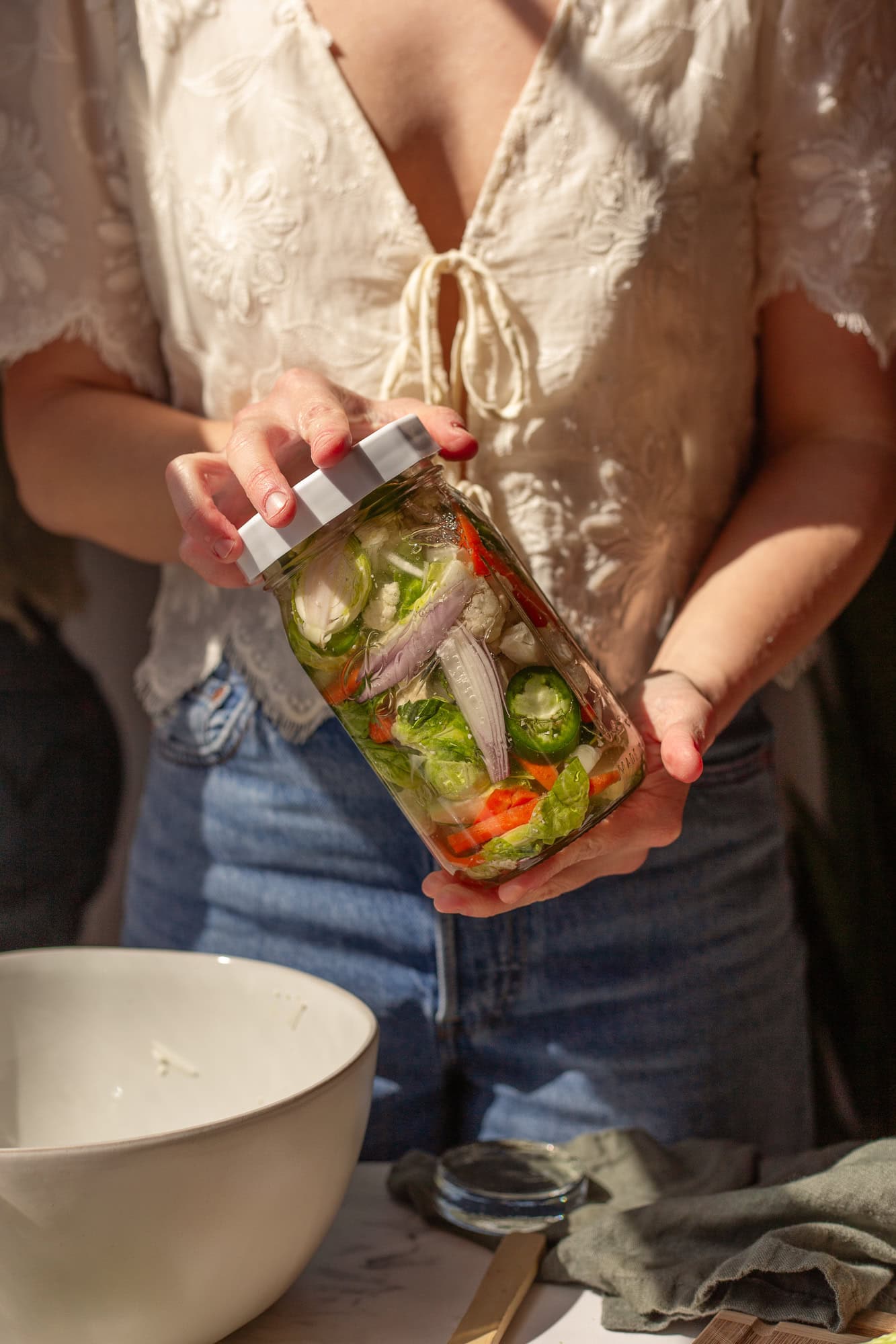 A person holding a jar of fermented giardiniera.