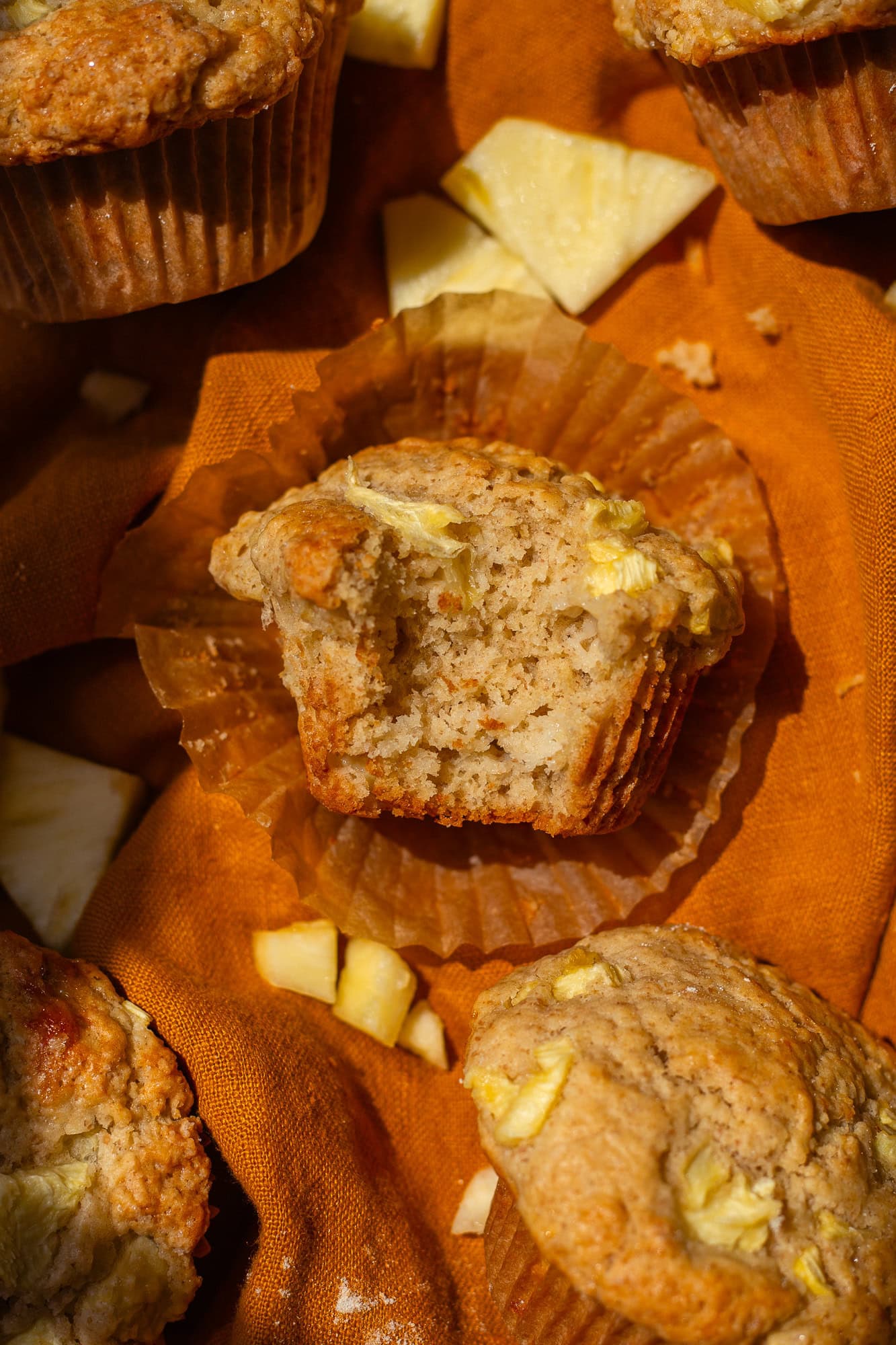 A close up of a sourdough pineapple muffin on an orange cloth.