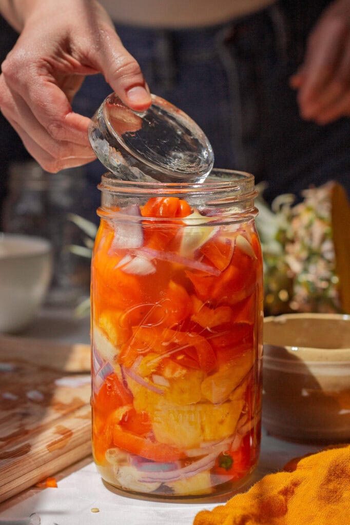 Placing a fermentation weight on top of the ingredients in the jar.