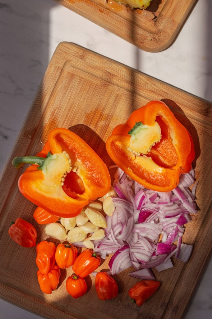 Chopped bell pepper, red onion, garlic and hardener peppers on a cutting board.