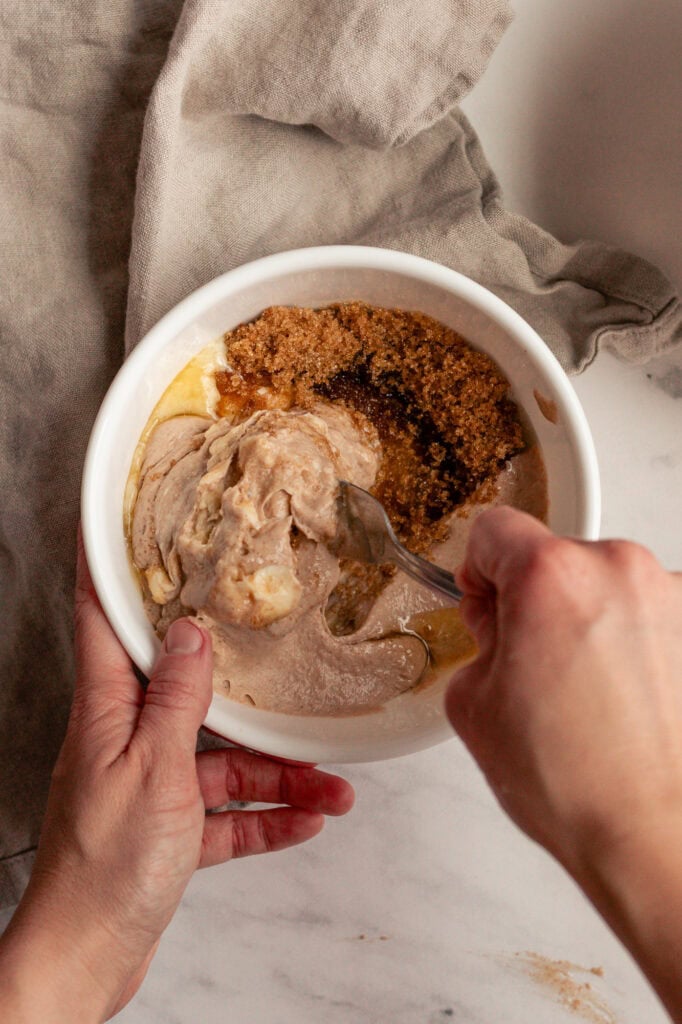 Wet ingredients before combining A bowl bowl contains the wet ingredients: honey, brown sugar, sourdough starter, and cubes of butter, before being mixed together.
