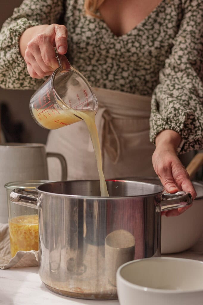 Pouring in Lemon Juice Hands pouring lemon juice into a stainless steel pot.