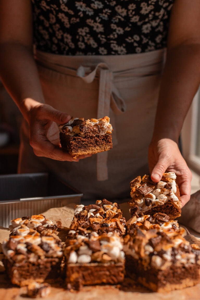 Hands cholding two sourdough s'mores brownies shocasing the toppings and the texture of the brownie.