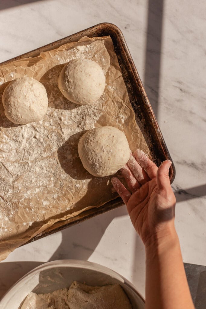 Finished dough balls are placed in a baking sheet to be formed into bagels.