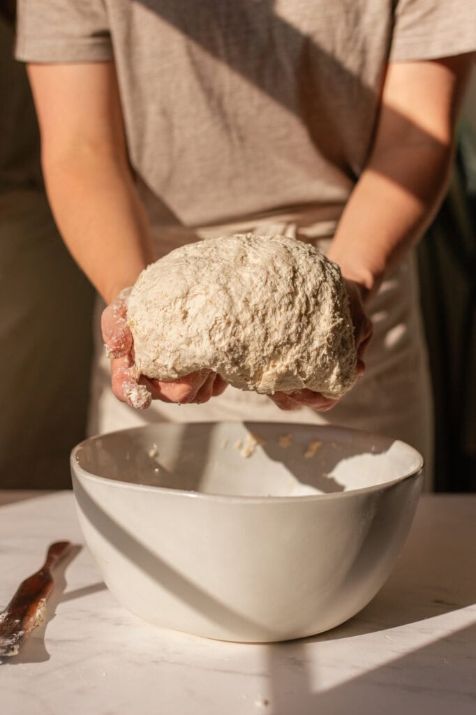 Hands holding the formed shaggy dough ball.