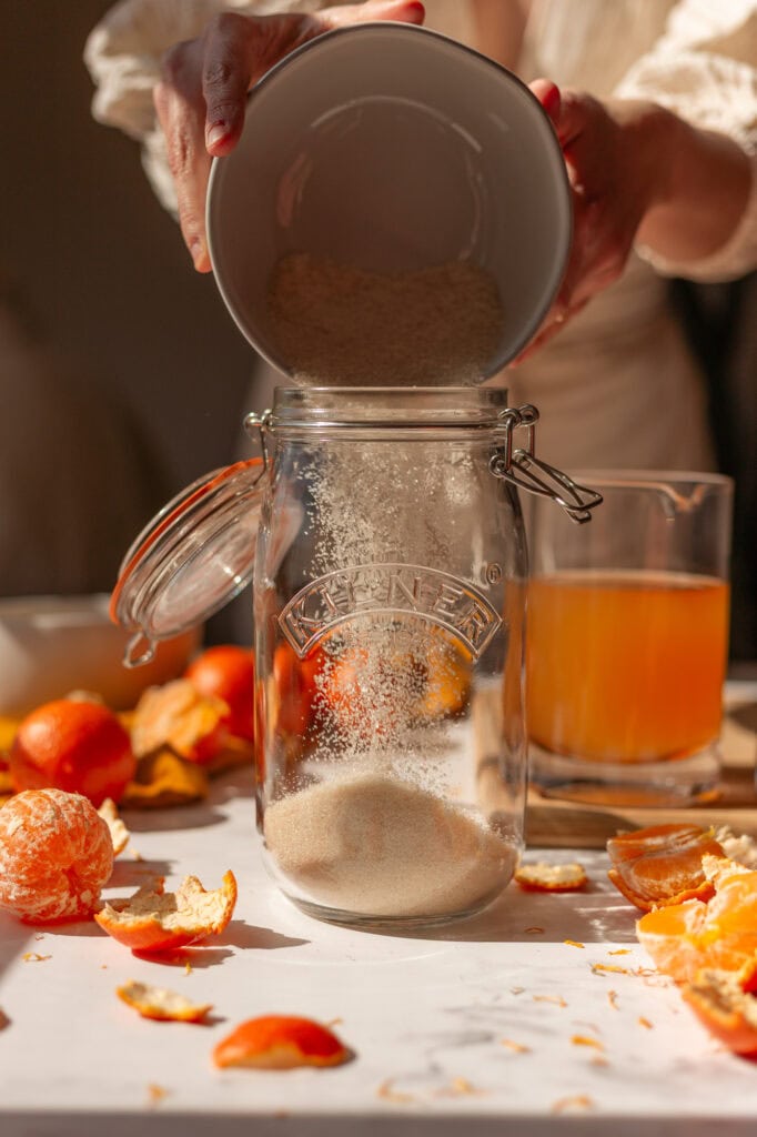 pouring 1 cup of organic granulated sugarnto a 1.5-liter clip top glass jar