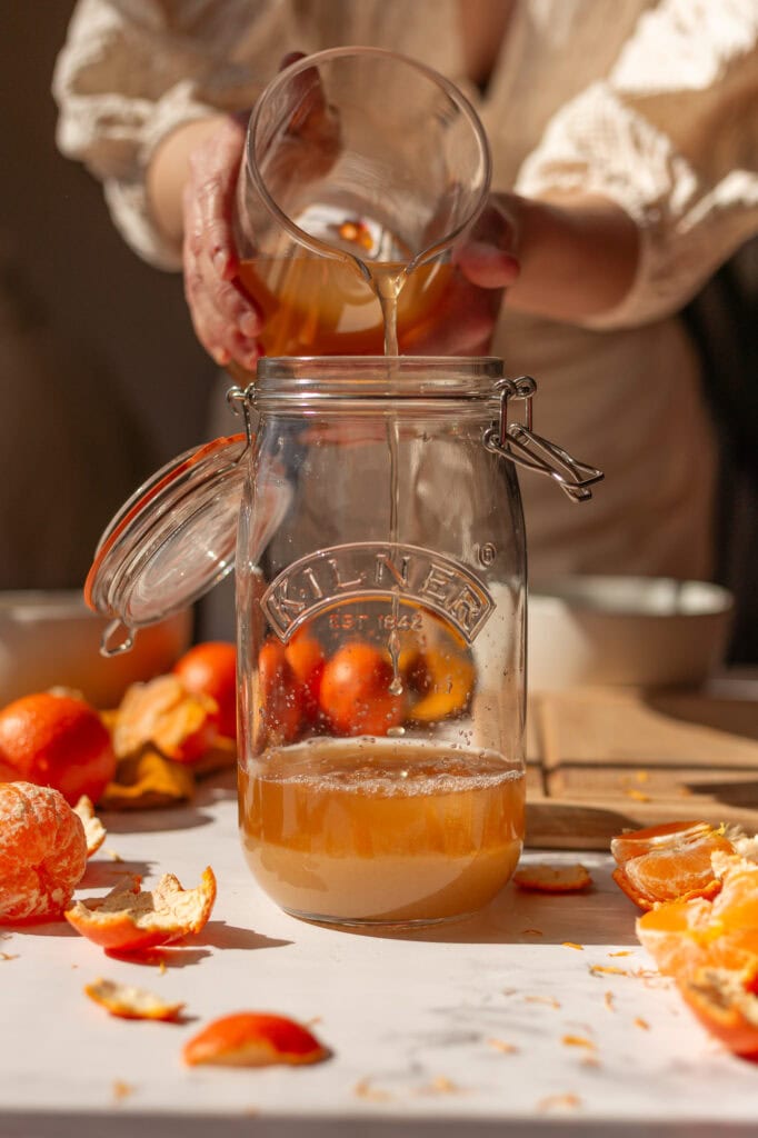 pouring 2 cups of raw apple cider vinegar into a 1.5-liter clip top glass jar