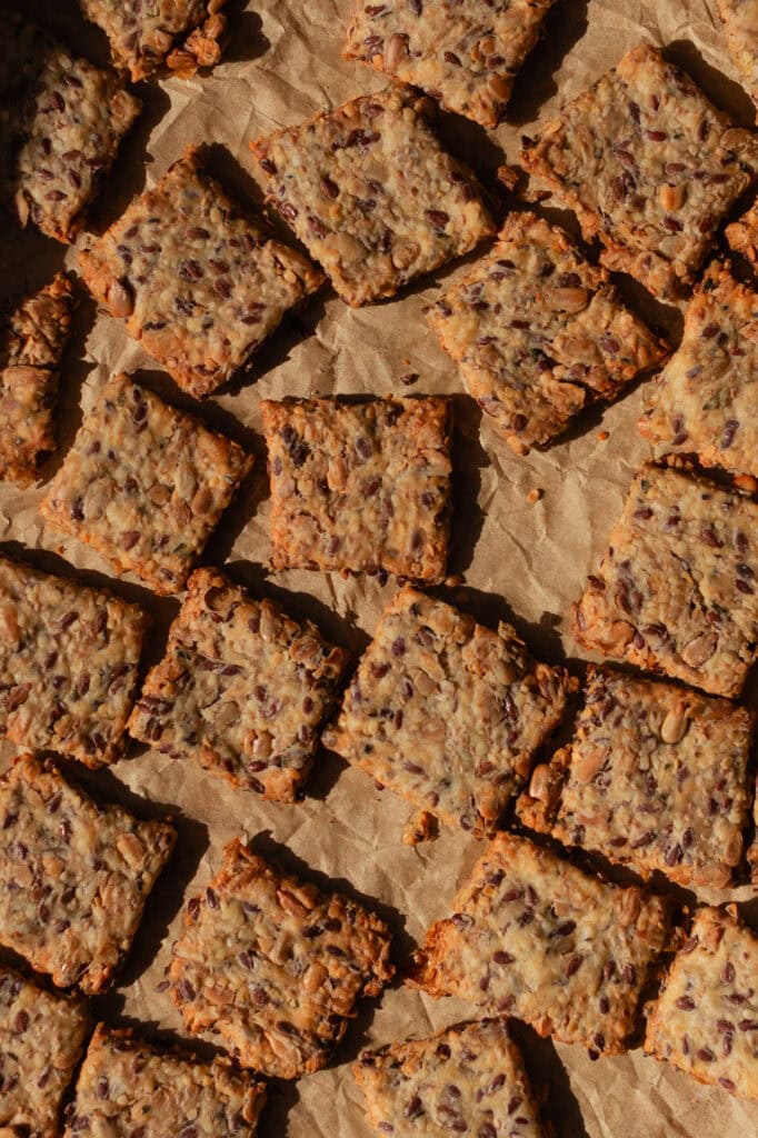 The finished seedy sourdough crackers cool on parchment paper.