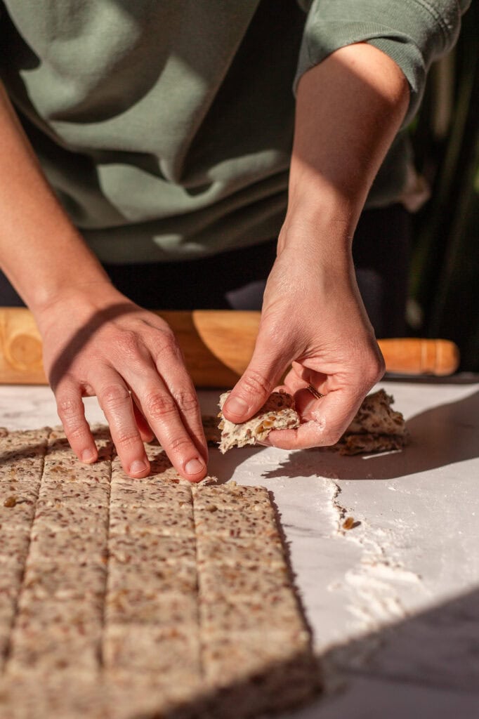 Hands begin to pull apart the divided squares of dough. 