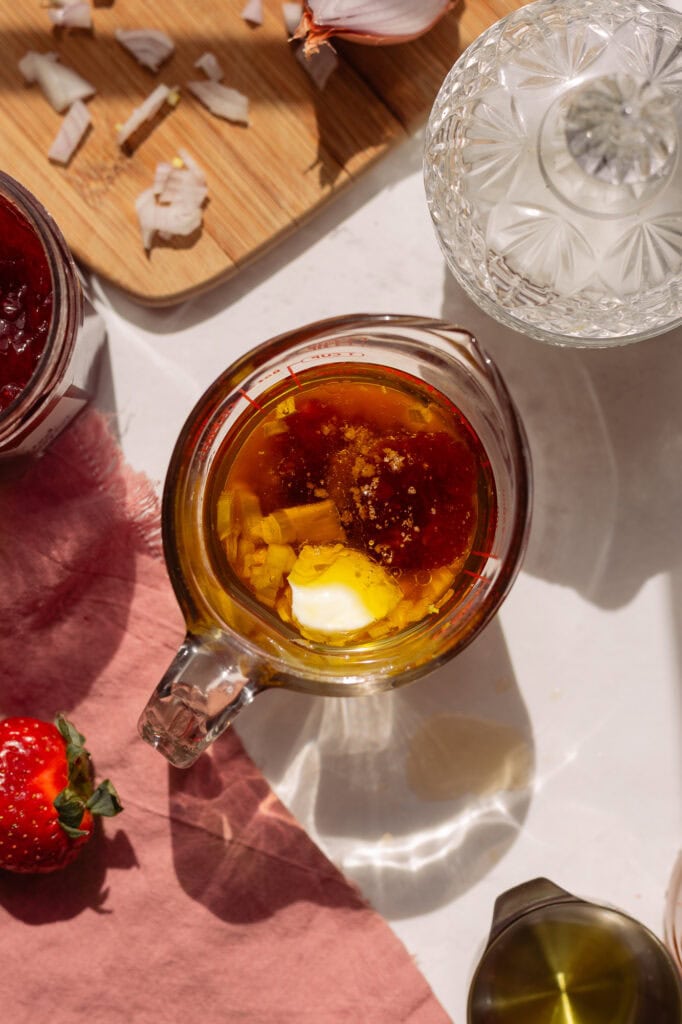 Olive oil, mayonnaise, vinegar, chopped shallot, strawberry jam, hot sauce and pickle brine in a glass measuring cup. The measuring cup is large enough to hold all the ingredients with room to use an immersion (stick) blender. 