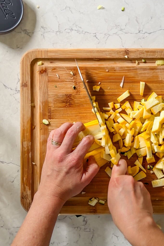 Raw squash being cut on a wooden cutting board