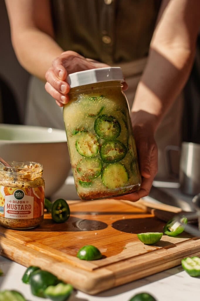 A packed jar of cucumbers and jalapeños is displayed.